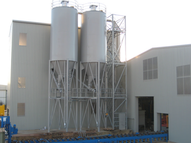 Two cement silos pictured outside a production facility.