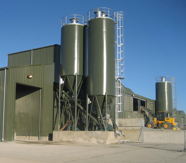 Three cement silos shown next to a concrete producing plant.