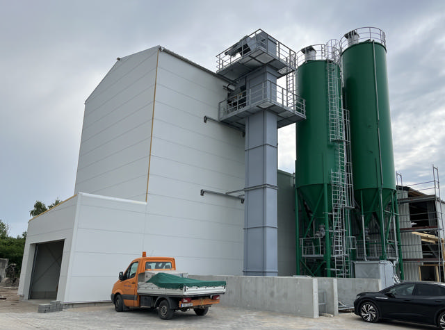 Grey bucket elevator installed on the outside of a production facility.