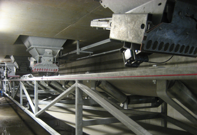 Grey moving weighing belt pictured in a production facility.