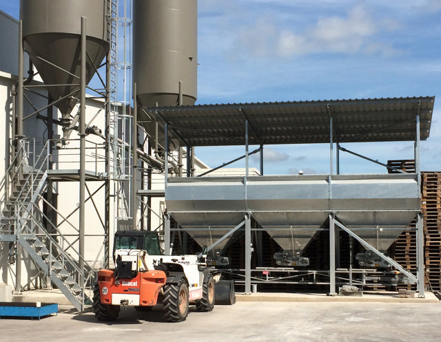 Three aggregate bins shown in front of a concrete plant.