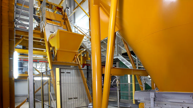 Yellow skip hoist shown in a concrete producing factory.