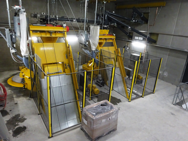 Two yellow skip hoists side by side in a concrete producing factory.