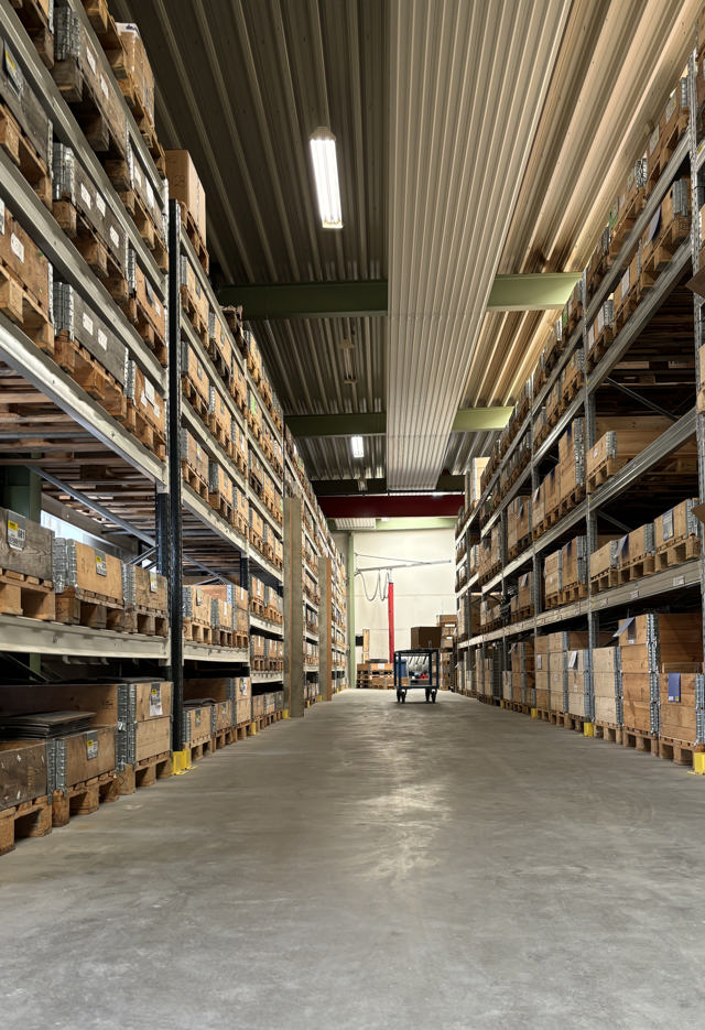 Picture of a long corridor with shelves on both sides filled with spare and wear parts.