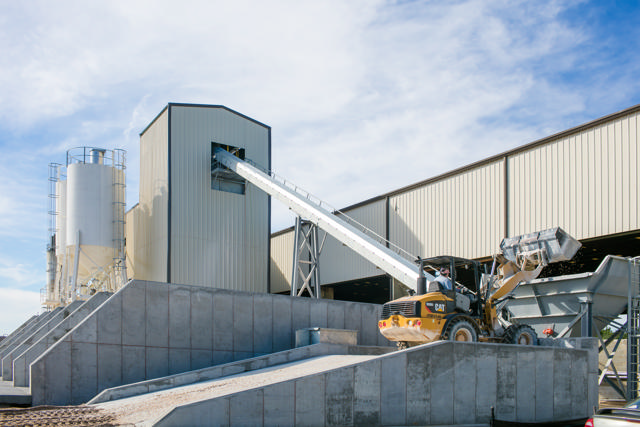 Truck unloading material on an inclined conveyor.