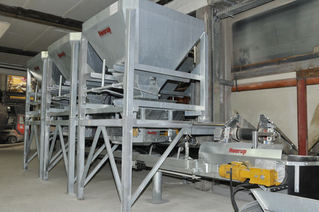 Three grey interchangeable hoppers pictured in a production hall.