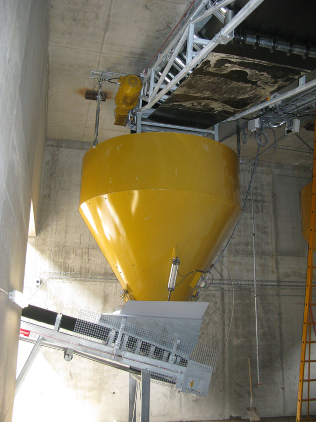 Yellow weighing hopper in a concrete production facility.